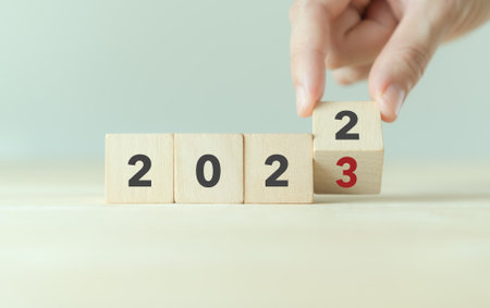 Beginning and start of the new year 2023. Preparation for happy new year ,new life, new business, plan, goals, strategy concept. Hand flips wooden cubes with  2022 to 2023 on smart background.の写真素材