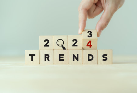 2024 trend concept. Hand flip wooden cube turn year 2023 to 2024. Beautiful white background, copy space. Used for the banner trend concept of the new year for monitoring new business opportunities.の写真素材