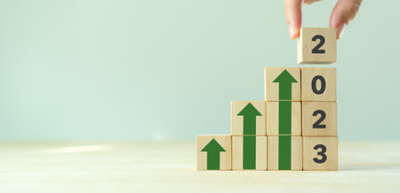 Business growth concept in 2023. Business goals and achievement. Sustain development. Wooden cubes inscripted 2023 and growth icons on smart background. Positive indicators and trend concept.の写真素材