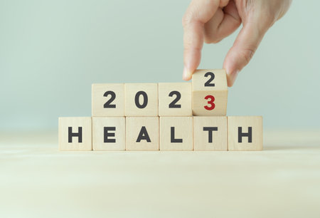 Health management and trend concept in 2023. Medical healthcare business and personal healthcare. Hand flips wooden cubes 2022 to 2023 with text "HEALTH" on beautiful grey background and copy space.の写真素材