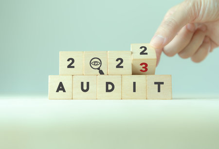 2023  annual audit business concept. Examination, evaluation financial statements; income statement, balance sheet, cash flow statement.  Flipping wooden cubes from 2022 to 2023 with audit icon.の写真素材