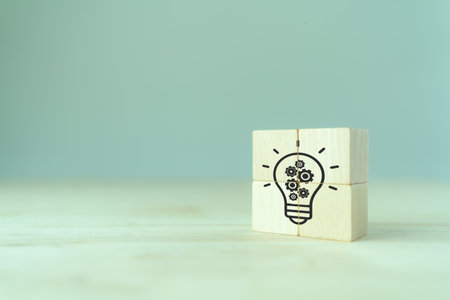 Creative idea, solution and innovation concept. Idea generation for business development. Wooden cube blocks with light bulb and gears icons on clean background and copy space.の写真素材