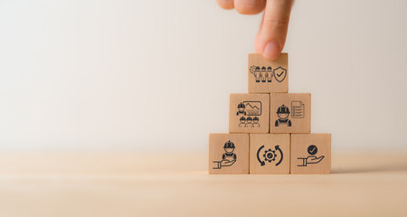 Work safety concept. Wooden cube blocks with icon of safety at workplace surrounded by safety first,...
