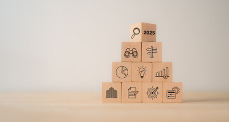 Economic, business outlook concept. Financial, business view or economic growth forecast for 2025. OUTLOOK 2025 text and business trend icons on wooden cube blocks, copy space, minimal background.の写真素材