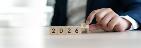 2026 new year business goals, challenge business target and business growth planning. Businessman arranges wooden blocks displaying the year 2026 along with icons strategic goals and financial growth.の写真素材