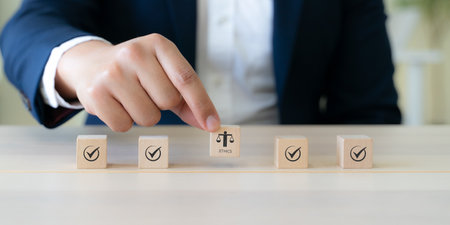 Ethical Assessment Concept. Placing wooden blocks with icons including checkmarks and a symbol of ethics, representing the evaluation and validation of ethical standards. Effective compliance.の写真素材