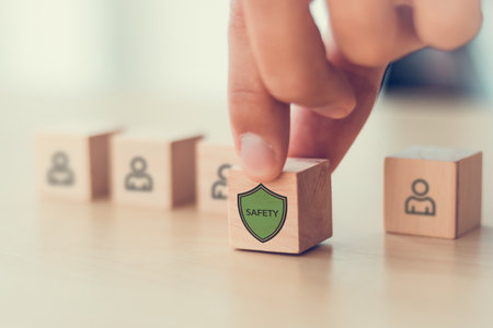 Workplace Safety Concept. Wooden blocks  with employeeor user icons and a security shield,...