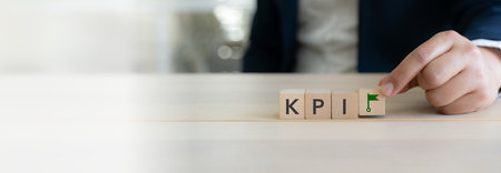 KPI and goal management. Measuring business performance effectively. Wooden blocks showing KPI letters and a green flag icon. Goal achievement, performance measurement, and business success.の写真素材