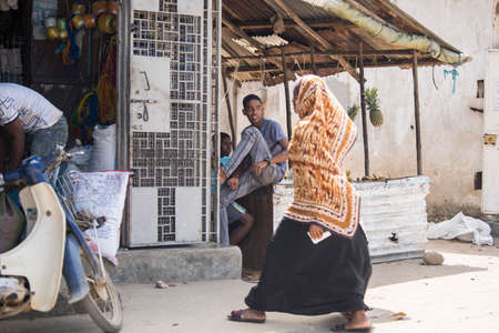 Zanzibar, Tanzania - January 05,2022: Street view of the usual daily life of local people all ages taking place along the road on the Zanzibar Island in Tanzania.のeditorial素材