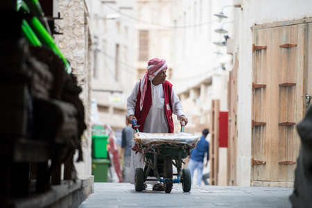 Doha, Qatar -May 25,2018: Wheel Barrow Worker in Souq Waqif, these workers are used to load goods since old traditional time.のeditorial素材