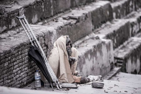 Kathmandu, Nepal- April 20,2019 : The cripple begs on the street of Pashupatinath Temple in...