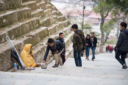 Kathmandu, Nepal- April 20,2019 : The cripple begs on the street of Pashupatinath Temple in...