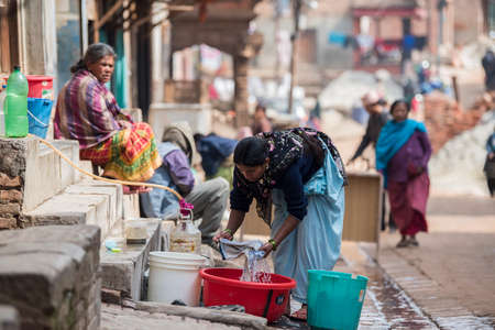 Unidentified Nepali woman washing clothes in the street.の写真素材