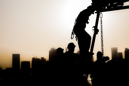 Doha,Qatar - December 11,2017. Construction workers preparing a crane for work in the background skyscrapers in Doha.のeditorial素材