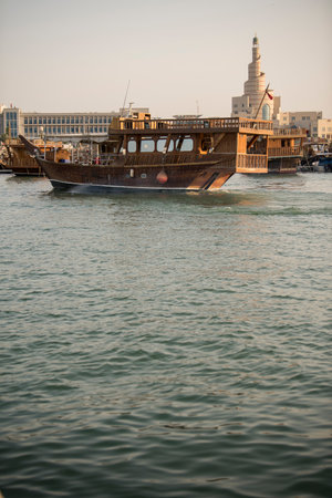 Doha,Qatar- April 24,2022 Traditional boats called Dhows are anchored in the port near the Museum of...