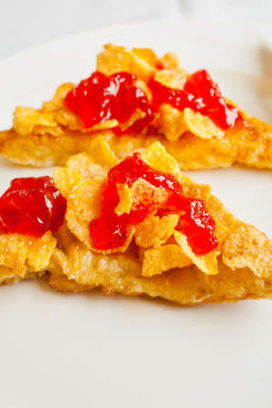Bread topped with honey and cereal with strawberry jam