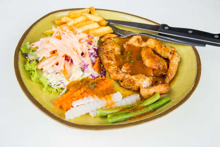 Chicken steak with vegetables and potato in dish on white backgroundの写真素材