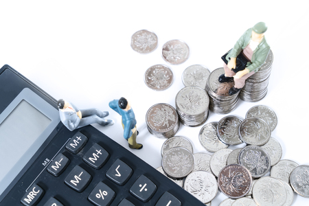 A businessman who thinks or makes a decision with a calculator and a coin.の写真素材