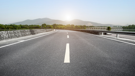 Asphalt highway and distant mountain green treesの写真素材