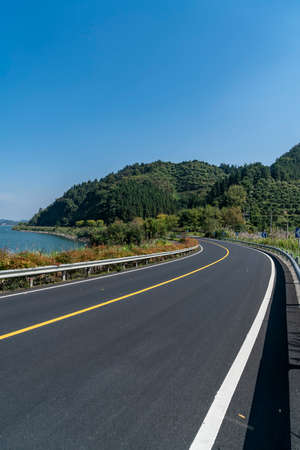 Asphalt road bend and green hills backgroundの写真素材
