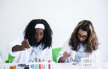 Happy african and caucasian child girl student with different skin is learning and test science...
