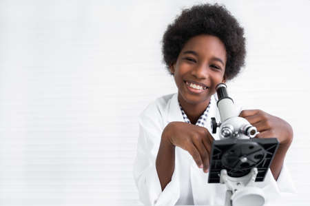 Portrait of happy African American child boy student is learning and test science chemical with colorful liquid by to microscope in laboratory room at school. Education and science research concept.の写真素材