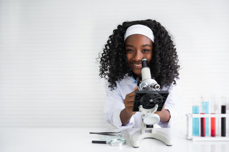 Portrait of happy African American child girl student is learning and test science chemical with colorful liquid by to microscope in laboratory room at school. Education and science research concept.の写真素材