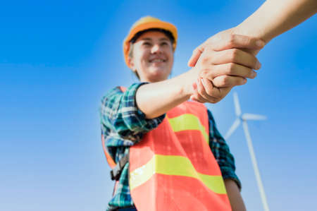 Happy engineer woman in uniform making handshake after successful about to installation wind...