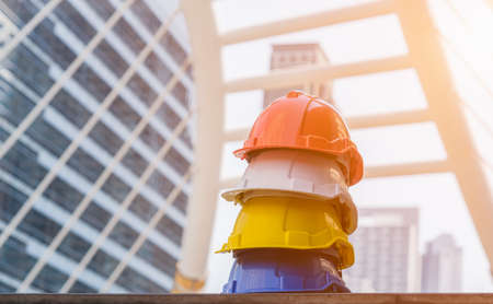 Stack of orange, white, yellow and blue hard safety helmet on floor in construction site. Personal...