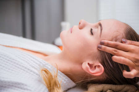 Beautiful young woman sleeping and relaxing with face massage and treatment in spa salon. Beauty of lady in spa salon getting face therapy in spa resort. Cosmetology course. Spa face massage concept.の写真素材