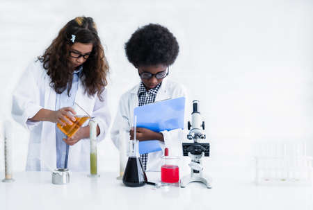 Two student are friends with different types of skin together learning and test science chemical with colorful liquid in beaker and test tube in laboratory at school. Education and research concept.の写真素材