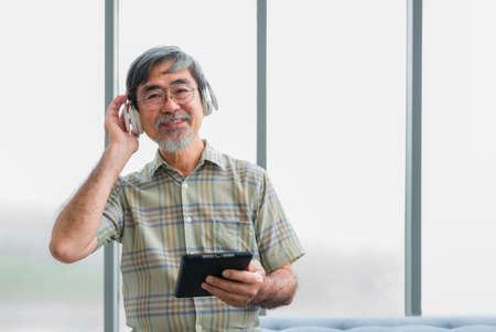 Senior old male wear red earphone and listening music. Lifestyle after retirement of elderly. Happy...