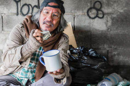 Happy homeless senior man from banknote and money by donation. Homeless old man wear sweater and...