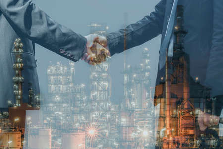 Double exposure of two businessman standing handshake on outdoors with oil and gas refinery plant petrochemical industry in asia industrial estate. Business partnership and teamwork concept.の写真素材