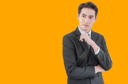 Portrait of asian handsome young businessman in suit standing posing and hairstyle in studio isolated on yellow background.の写真素材