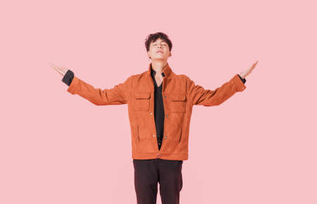 Portrait of asian handsome young man standing and hands up with close your eyes begging from god...