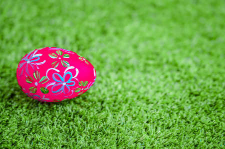 Beautiful pink Easter egg on green grass background. Easter day concept.の写真素材