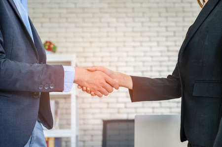 Businesswoman and businessman standing with making handshake after successful about to partnership. Business partnership meeting and teamwork concept.の写真素材