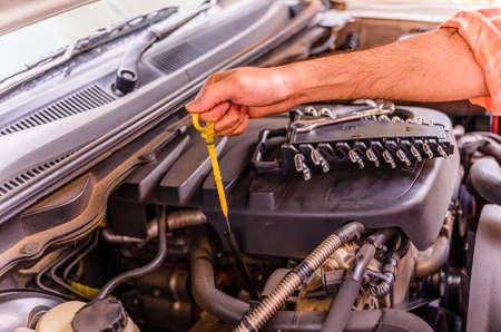 Male mechanic checking car engine oil level and change car engine oil with car service repair in outdoors.の写真素材