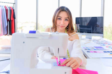 Beautiful asian woman tailor and seamstress sews working in fashion by sewing machine. Designer and...