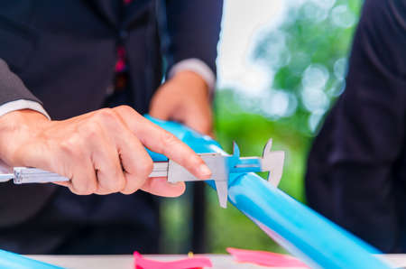 Engineer checking diameter of blue pvc pipe by manual vernier caliper.