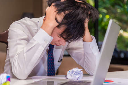 Asian young businessman failing and stressed in office about his business. Business and finance...