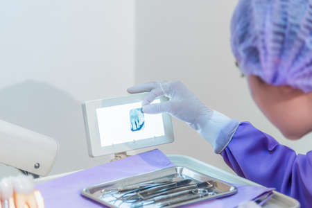 Woman dentist holding and checked x-ray film of dental in clinic.