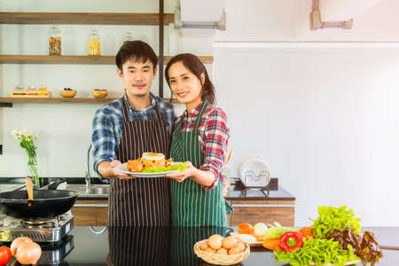 Asian couples are preparing American fried rice a healthy breakfast with happiness in the kitchen at their home. Healthy and lifestyle concept.の写真素材