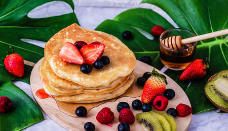 Classic american pancakes with fresh berry, honey, strawberry and ingredients on the wooden background.の写真素材