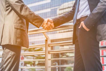 Two businessmen shaking hands on outdoors with city background. Bussiness partnership concept.の写真素材