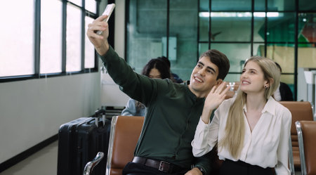 Happy young couple tourist using smartphone taking selfie and video together while waiting for...