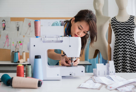 Attractive Asian woman designer dressmaker or fashion seamstress tailors working setting up and...