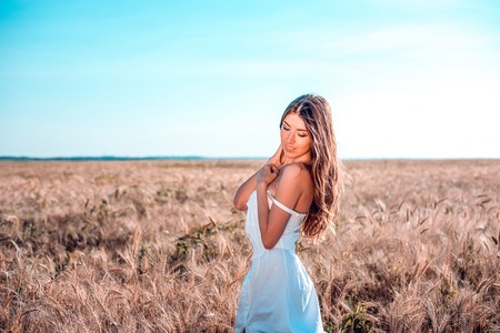Happiness nature summer vacation - young woman in a white dress field sunny day in nature, the concept of tenderness. Feminine silhouette of tanned skin.の写真素材
