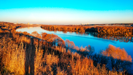 Beautiful scenery of the Oka river in Kolomna, autumn panorama, bright autumn in November. Golden trees, blue sky. Bright reflection of trees in the river. The lake goes into the distance.の写真素材